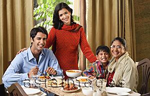 Asia Images Group - woman stands over dinner table with smiling family