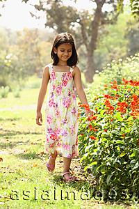 Asia Images Group - Young girl walking next to flowers