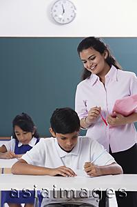 Asia Images Group - two students at desk, teacher standing