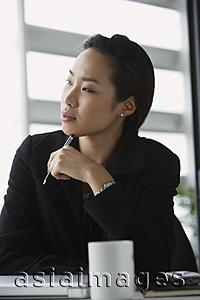 Asia Images Group - woman at desk, pen to chin