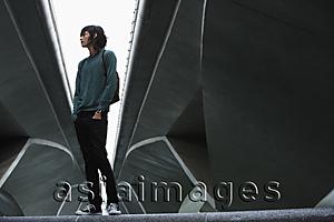 Asia Images Group - young man with backpack, standing under bridge