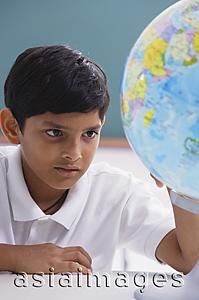 Asia Images Group - boy looks at globe, one hand on globe