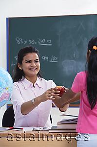 Asia Images Group - student handing apple to teacher