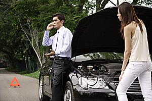 AsiaPix - Woman looking under hood of car while man talks on phone