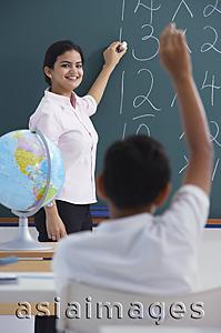 Asia Images Group - teacher at chalkboard, boy raises hand