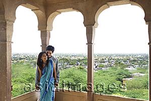 Asia Images Group - young couple leaning against pillar on terrace balcony