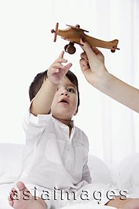 Asia Images Group - baby boy reaching for toy airplane