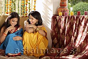 Asia Images Group - two young women chatting, wearing saris