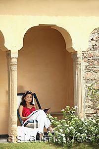 Asia Images Group - woman reading on patio