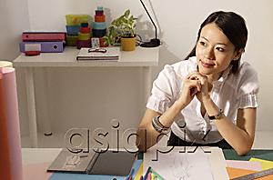 AsiaPix - Chinese fashion designer smiling, thinking at work desk