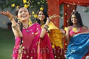 Asia Images Group - three women in saris, throwing petals