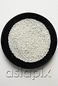 AsiaPix - uncooked grains of rice spread out on a black plate
