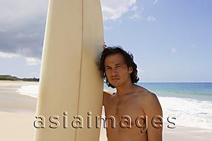 Asia Images Group - man standing next to surf board on the beach