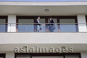 Asia Images Group - businessmen at balcony shaking hands
