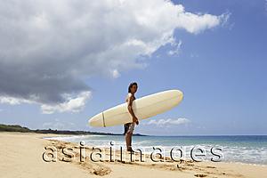 Asia Images Group - man standing on beach, holding surf board