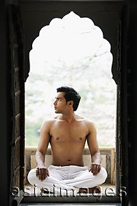 Asia Images Group - young man sitting cross legged, in doorway