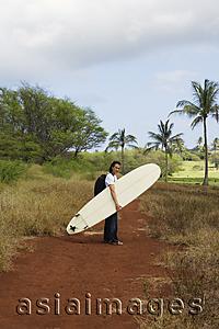 Asia Images Group - man walking on trail with surf board
