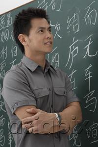 AsiaPix - man standing in front of Chinese characters written on chalk board