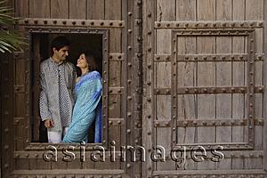 Asia Images Group - young couple at window in huge wooden doorway