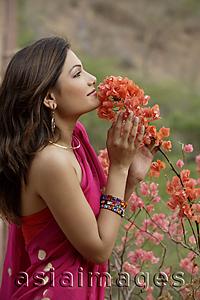 Asia Images Group - young woman in sari, smelling flowers