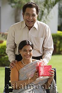 Asia Images Group - woman holding gift, man with hands on her shoulders