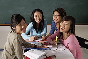 AsiaPix - Four young women studying together and laughing.