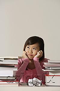 AsiaPix - Young woman sitting at desk with books looking sad.