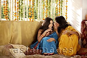 Asia Images Group - two young women gossiping, wearing saris