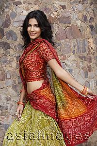 Asia Images Group - young woman in sari, stone wall