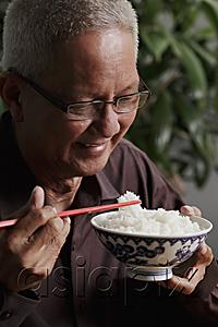AsiaPix - profile of mature man holding chopsticks and bowl of rice