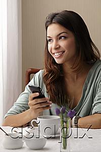 AsiaPix - young woman texting on phone a cafe