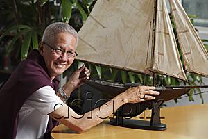 AsiaPix - older man with model sail boat