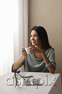 AsiaPix - young woman holding coffee cup and looking out window smiling