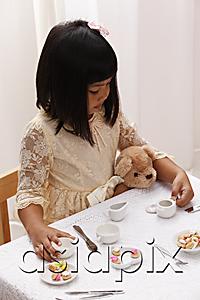 AsiaPix - young girl having a tea party with her teddy bear