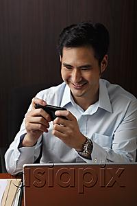 AsiaPix - man sitting at desk and looking at phone and smiling