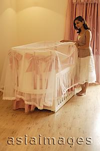 Asia Images Group - mother looking into baby crib