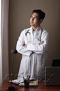 AsiaPix - male doctor standing at his desk looking out window