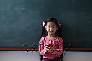 AsiaPix - Young girl holding a red apple in front of chalk board