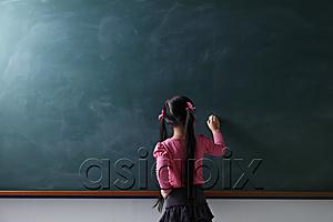 AsiaPix - rear view of young girl writing on chalkboard