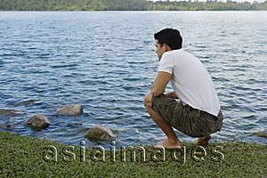 Asia Images Group - Man bending down next to lake