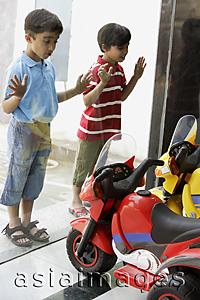 Asia Images Group - boys looking at toy motorcycles through the shop window