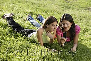 Asia Images Group - two teen girls in park, looking at text messages