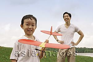 Asia Images Group - Father watching son holding toy airplane