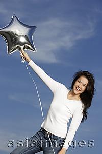 Asia Images Group - Young woman with silver star-shaped balloon
