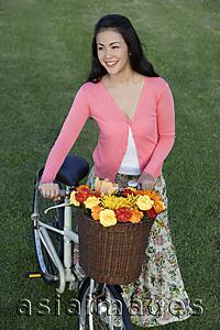 Asia Images Group - Young woman pushing bike with basket full of flowers