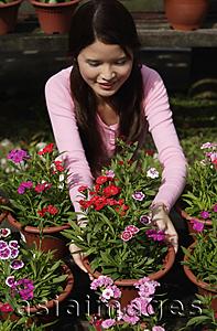 Asia Images Group - Young woman picking up a flower pot