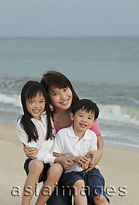 Asia Images Group - Young woman hugging boy and girl on beach