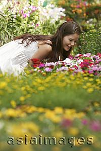 Asia Images Group - Young woman leaning over to smell the flowers