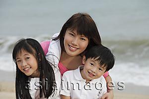 Asia Images Group - Young woman hugging boy and girl on beach