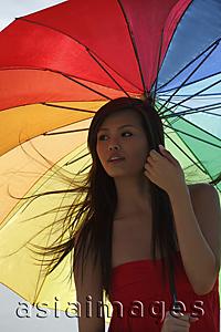 Asia Images Group - Young woman standing under bright umbrella
